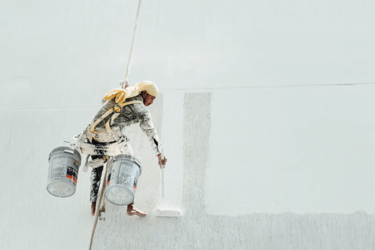 man in harness painting building exterior white