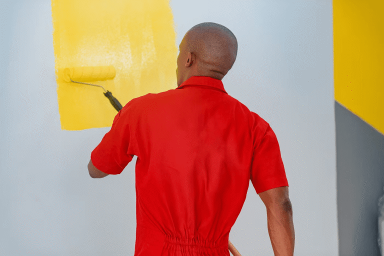man in red tee painting wall yellow